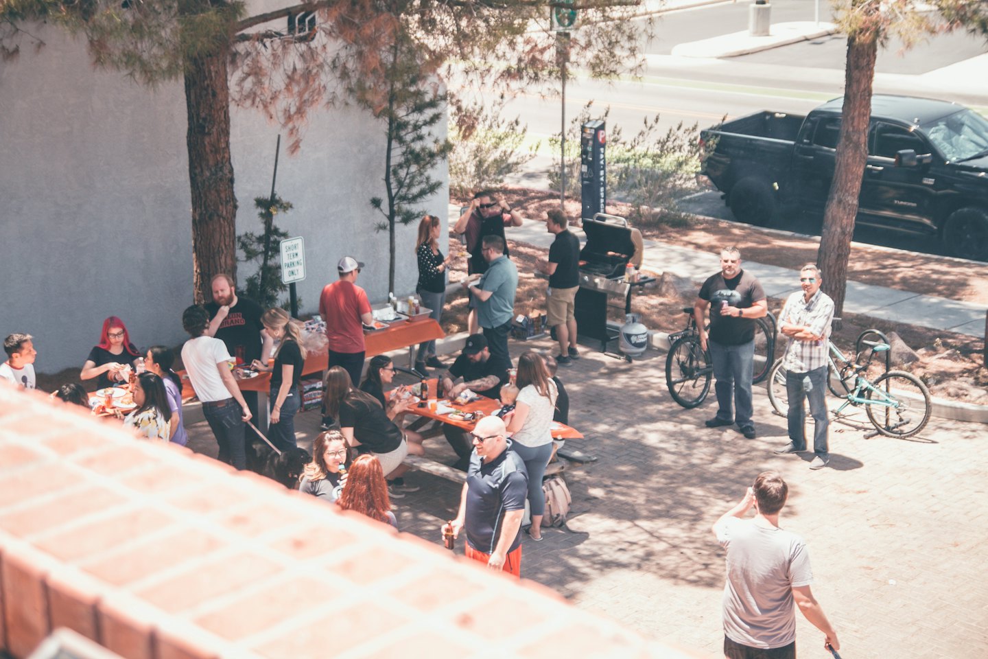 Adults gather and eat at an outdoor barbecue picnic.
